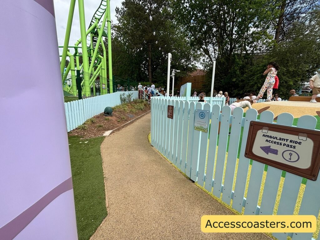 image of entrance to ride access pass queue signage directing guests to the queue reads ambulant ride access pass another sign for the same queue reads fast track entrance there is a ride access check in point on the fence. you can sea the path curving around to form the queline