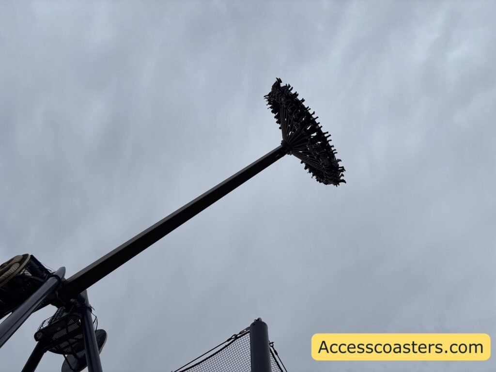 Close‑up of Aviktas’s long black arm raised high against a cloudy sky, with the rectangular passenger gondola at the tip tilted for a swing