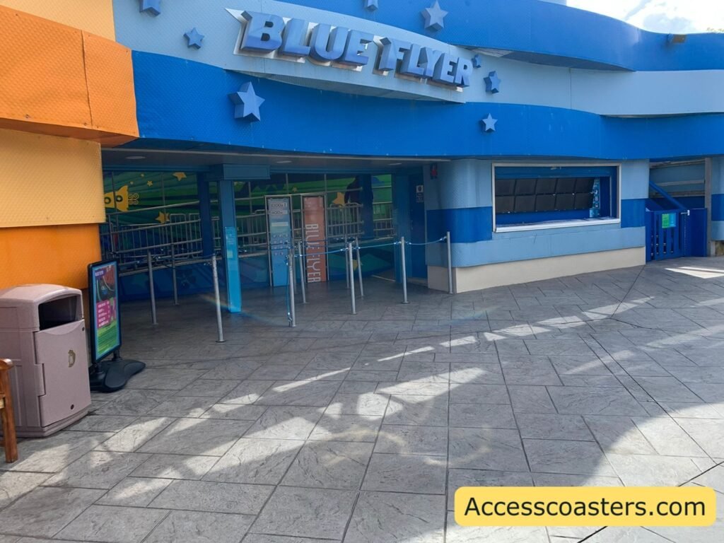 wide image of blue flyer you can see the ride entrance and queue line the photo both and the gate for the easy access pass entrance all are themed blue