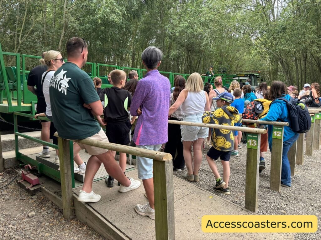 image of people batched into a loading area wating to get on a green trailer.  