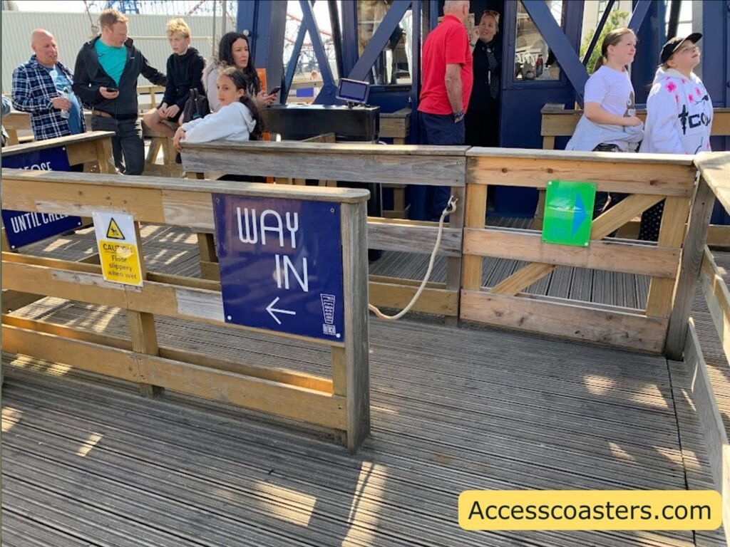 wooden queue line in ride station in a cattel pen style with sign that reads way in and additional sign with an arrow saying easy access pass entrance with a seprate straight queue line for easy access pass users