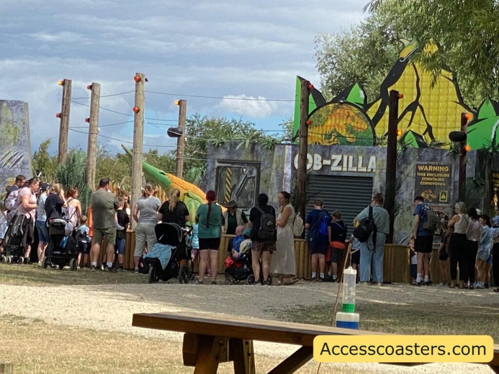 image of people gathered in a cercle formation behind a barrier watching a dinosaur show the dinosaur is partly visible.  