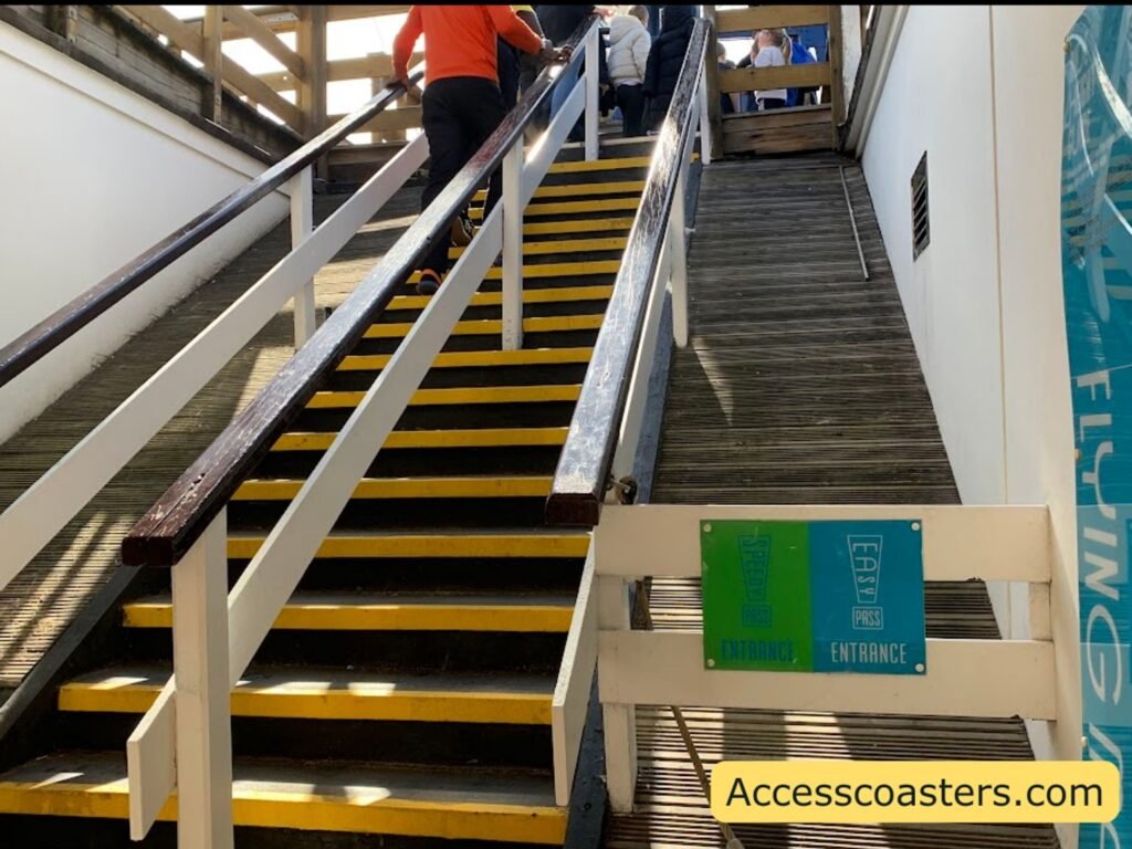 Flight of stairs with yellow-edged steps and handrails on both sides leading up to the Flying Machines station, with a sign at the bottem that says easy access pass entrance 