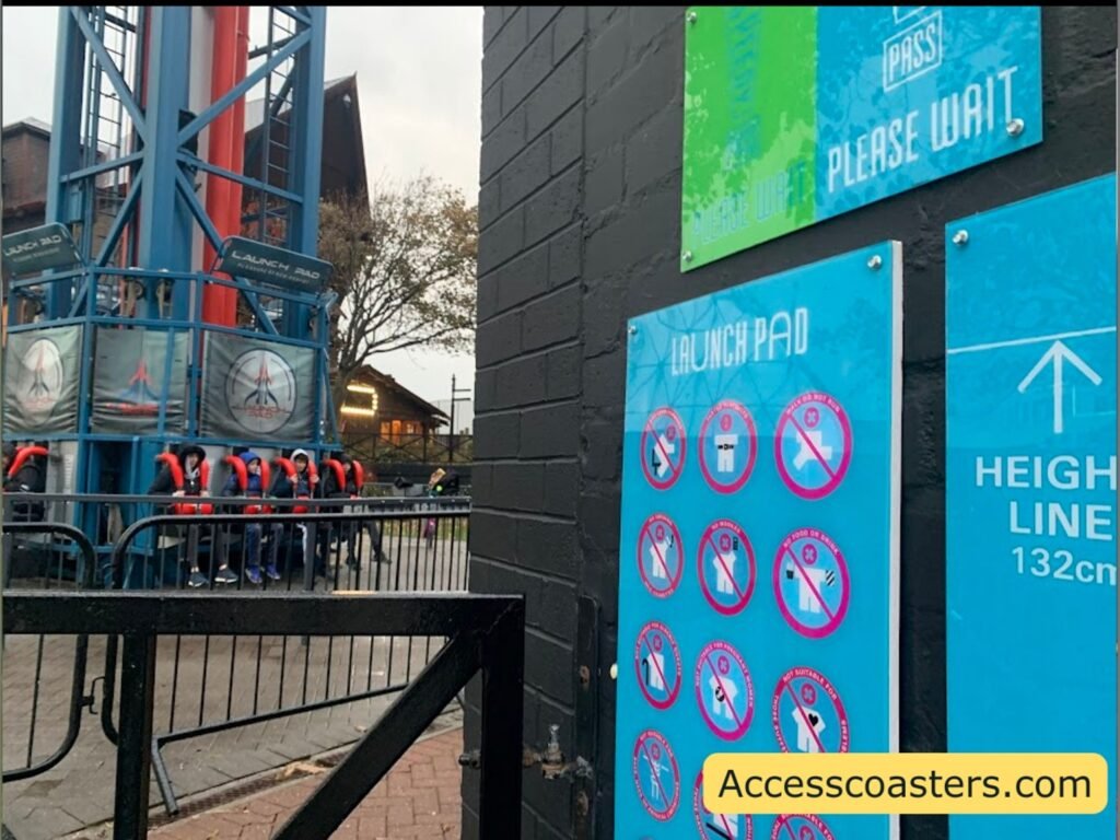 view from easy access pass gate with easy access pass entrance signage and ride restrictions vidable as well as base of lauch pad 