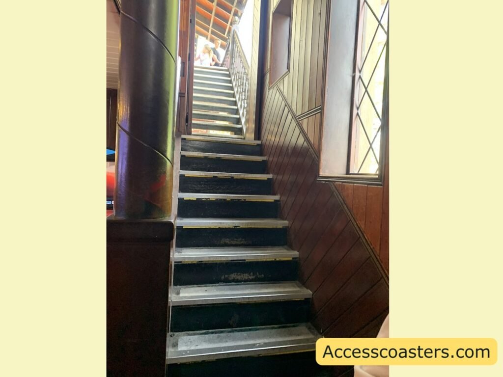 Flight of indoor stairs with contrasting step edges and a handrail on one side and natural light coming from windows at the top.