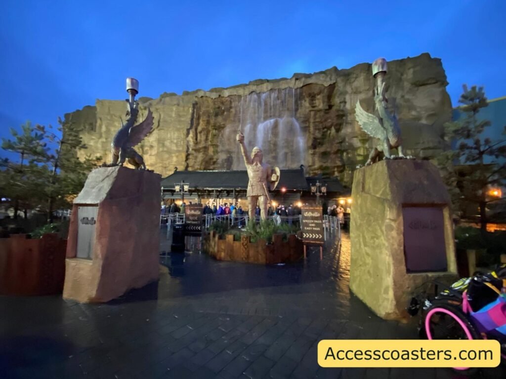 entrance plaza for vallhall with stone building and waterfalls visable as well as stone viking statues 