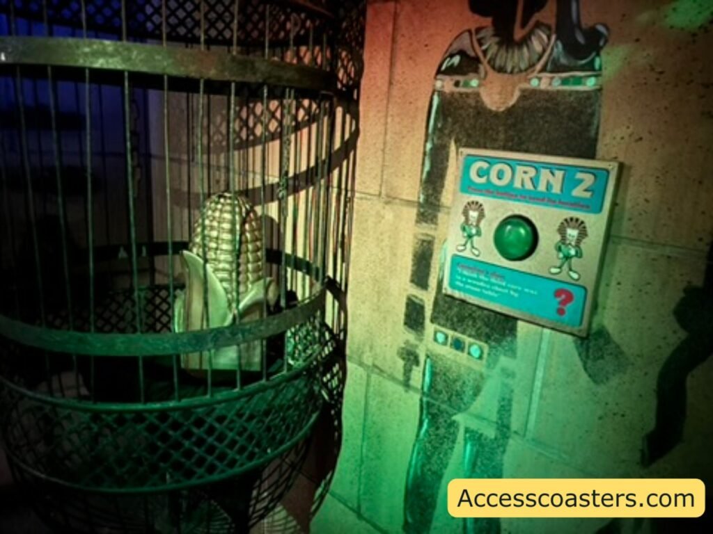 image of a golden corn on the cob inside a jail style case with a sign that reads corn 2 and has a button to press. 