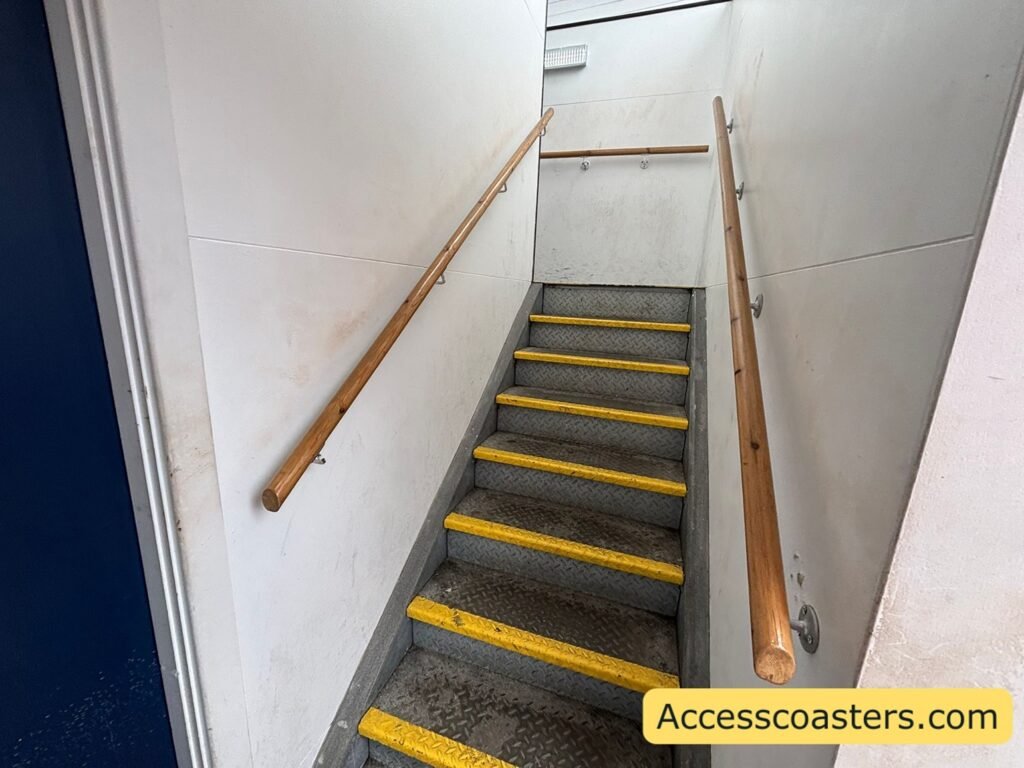 Narrow internal staircase on the easy access route, with yellow-edged steps and handrails on both sides