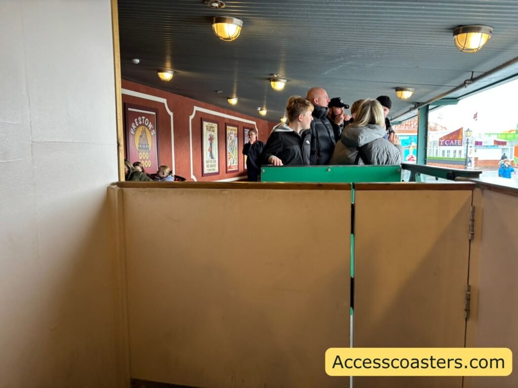 image shows front of easy access queue line you can see a gate with the ride area to the left and the main queue directly opposite the easy access entrance. 