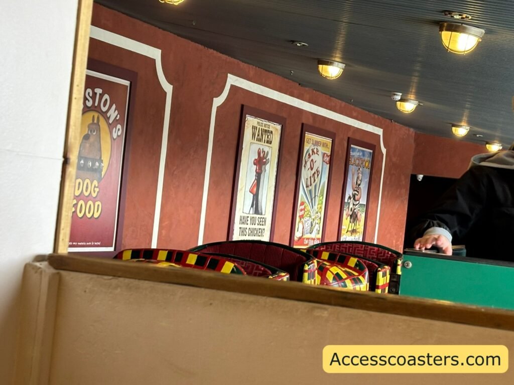 image shows close up of ride area from front of easy access queue line you can see 2 ride carts in the station themed to slippers both with 2 rows of seats. 