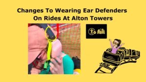 fetured image with text that reads Changes To Wearing Ear Defenders On Rides At Alton Towers and image in the middle of Iona wearing ear defenders with a tether attached. there is the information post symbol and a cartoon image of iona riding a rollercoaster with her hands in the air