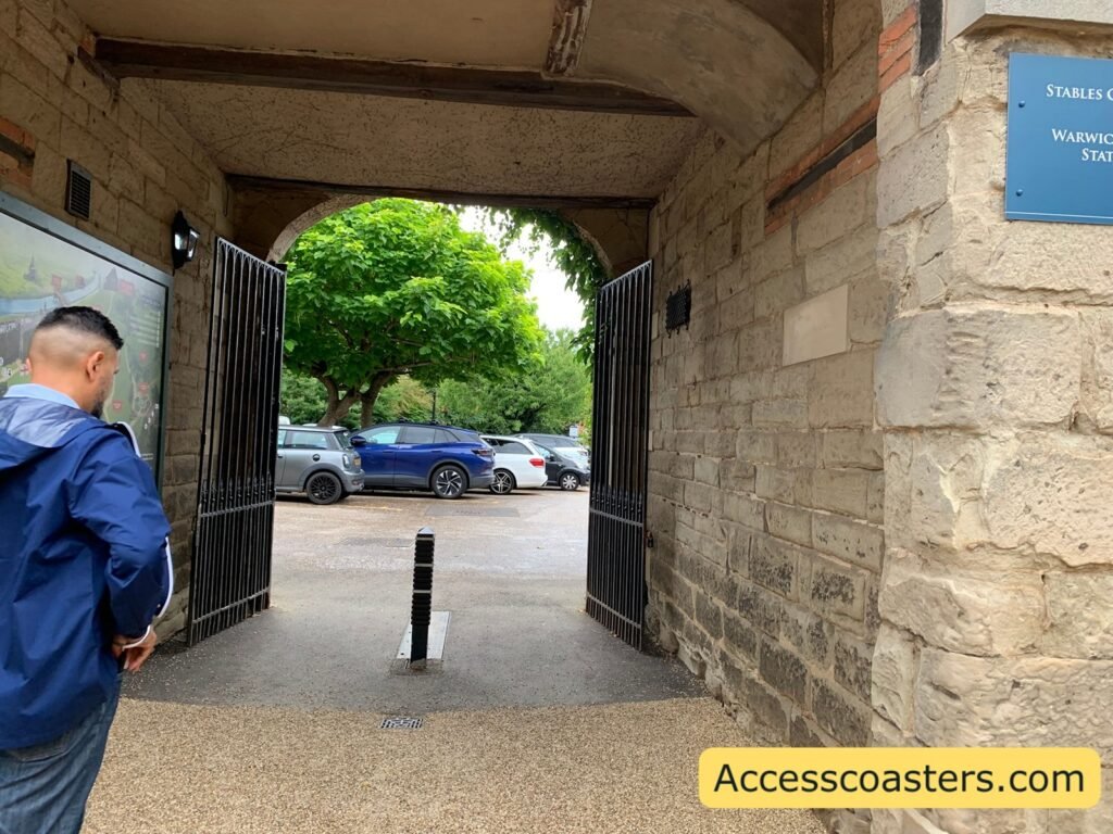 image of stone archway with black gates and map on the wall leading to a car park  