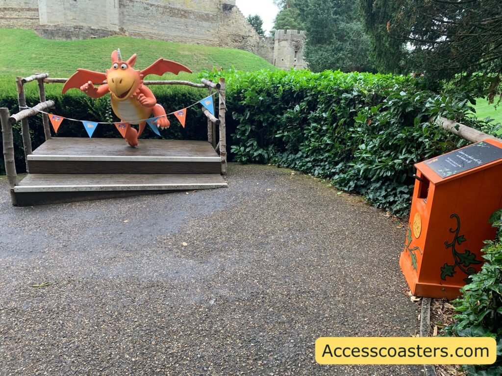 image of a Zog sculpture on a platform looking like he's flying with bunting around and a stamp machine in  the corner. 