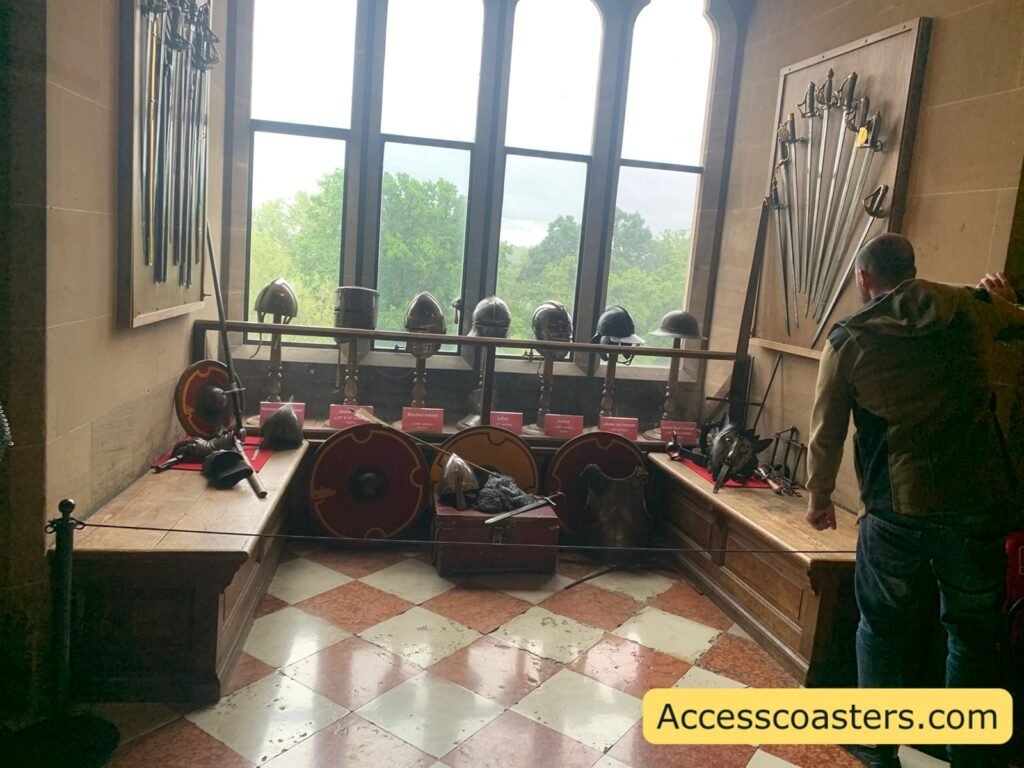 Window bay in the Great Hall with a chequered floor, large mullioned window, and a low platform lined with shields, helmets, and polearms, showing more of the historic arms and armour collection,