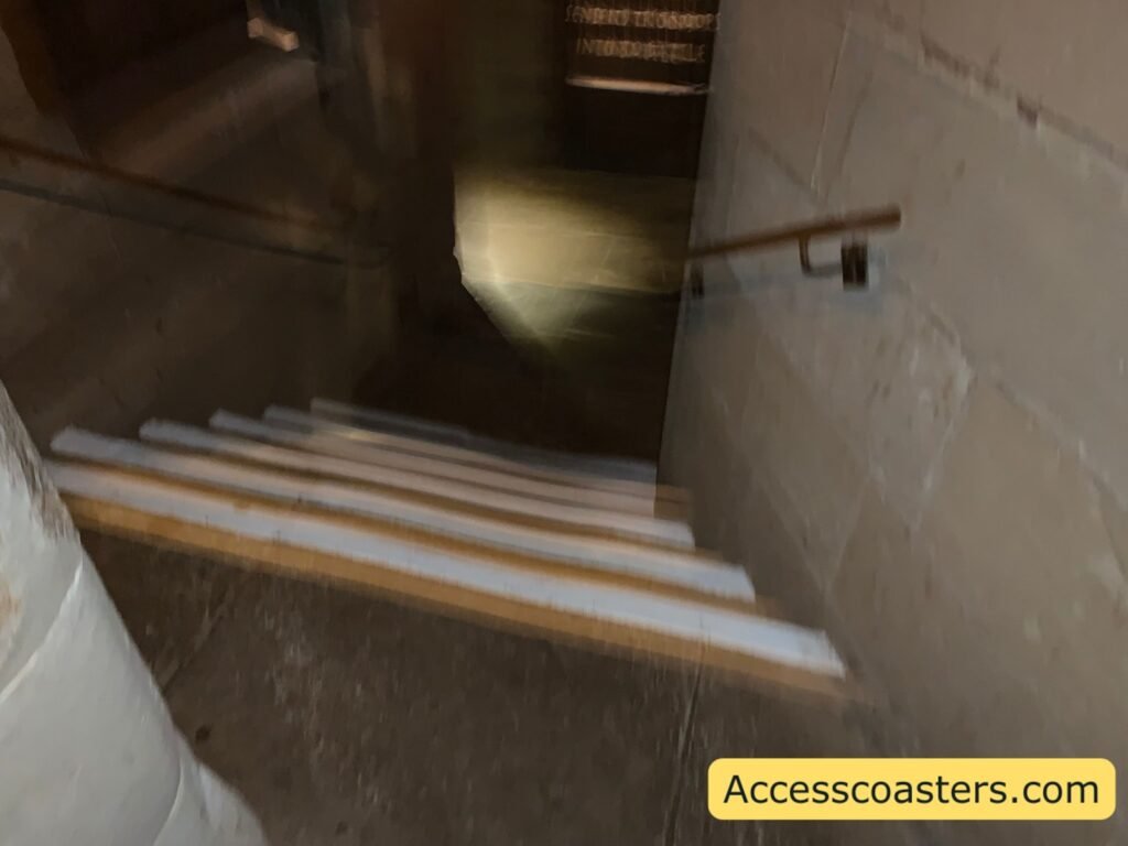 Narrow indoor staircase within The Kingmaker, with around half a dozen shallow steps, contrasting white step edges and a handrail on both sides