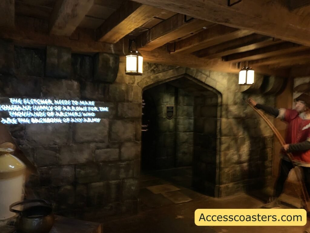 Dark stone corridor inside The Kingmaker with heavy wooden beams, doorway to the next room and white projected narration text on the wall