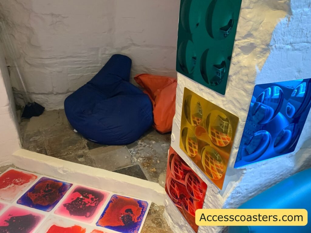 Beanbag corner inside the Welfare and Sensory Room with a large dark blue beanbag, an orange cushion and bright coloured sensory gel panels and sensory wall panels .