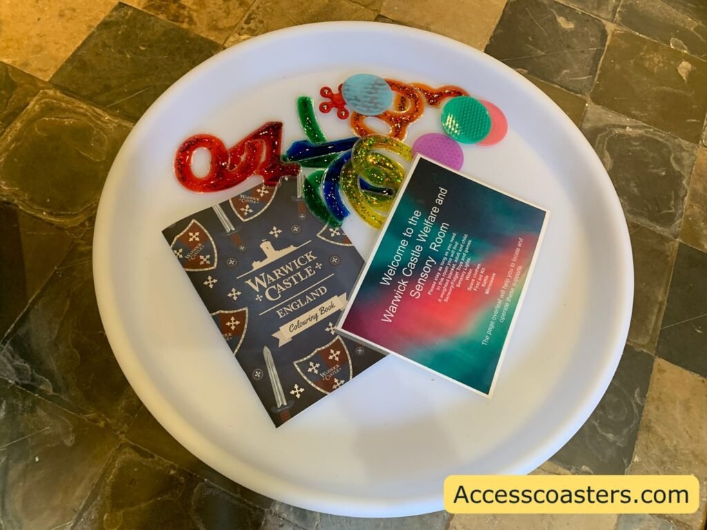 light table inside the room laid out with sensory and fidget items, including colourful textured coils, shiny ribbons and printed leaflets about the Warwick Castle Welfare and Sensory Room.