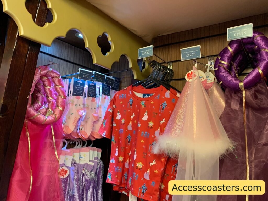 Rack of brightly coloured children’s princess and fairy costumes at Warwick Castle, including pink and purple dresses, capes and a pale tutu-style skirt.