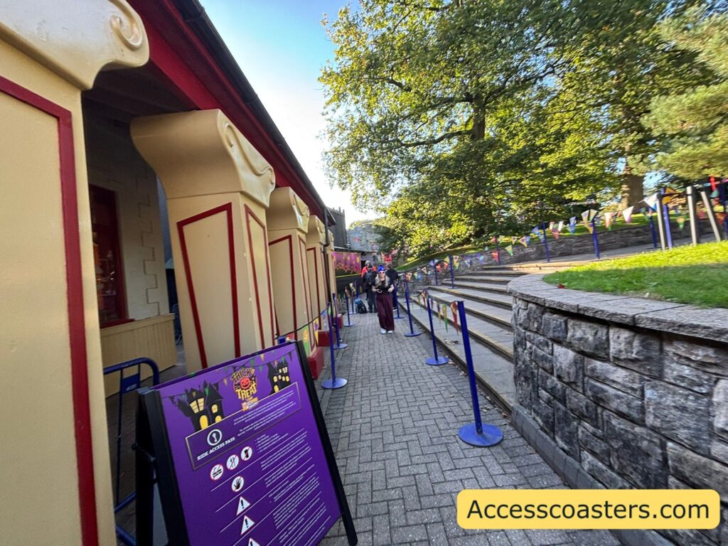 image of ride access pass entrance for trick or treat town with a restriction board outside with disabled information and a queue line area roped off by bunting. 