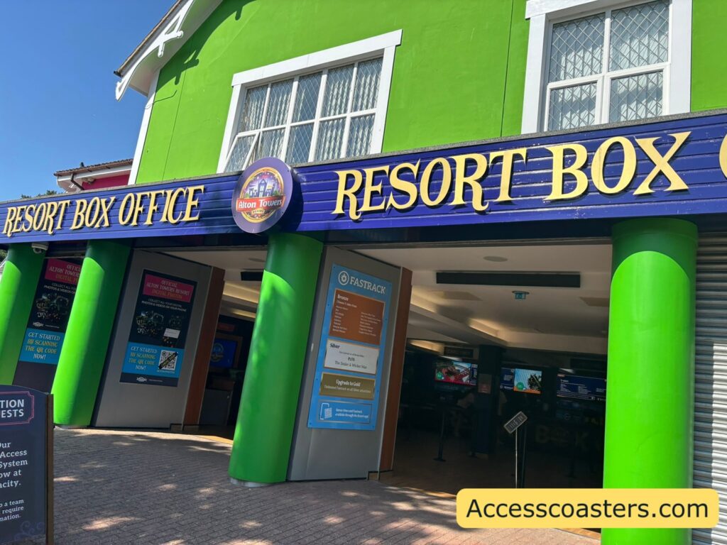 image of a green building with a big blue sign across the double entrance that reads resort box office. you can see lots of digital screens and counters inside. 